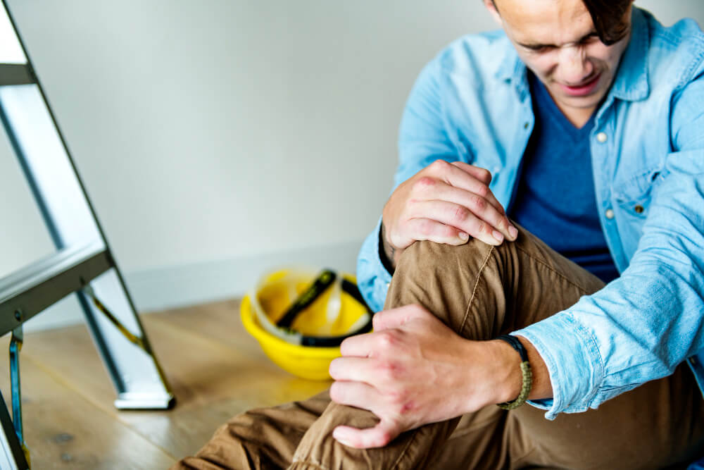 Verletzter Handwerker hält sein Knie fest